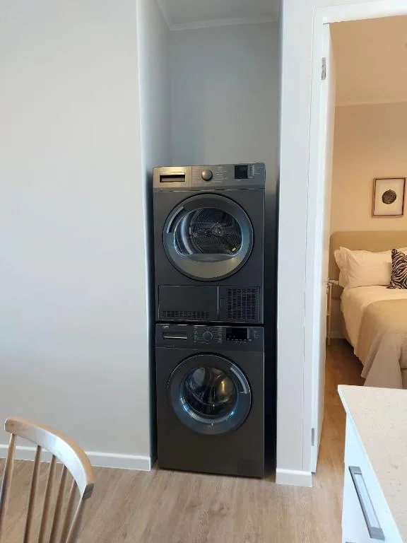 Stacked black washing machine and dryer in compact utility nook