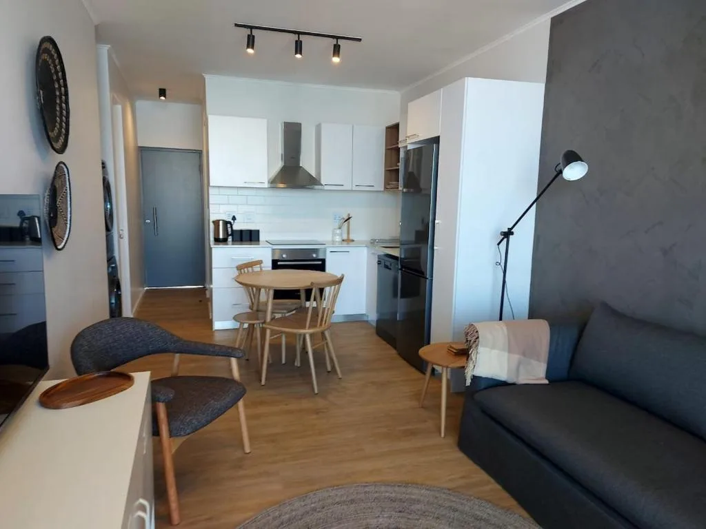 Modern living room with black sofa, wooden dining table, and open kitchen