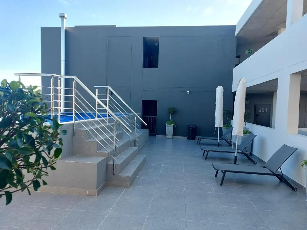 Modern patio with loungers, umbrellas, and contemporary architecture
