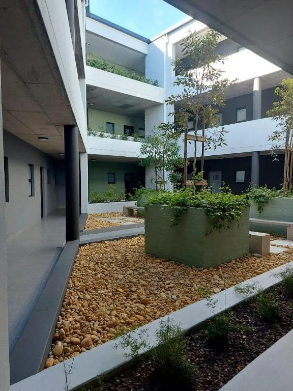 Modern apartment courtyard with white building, planted containers, and gravel landscaping