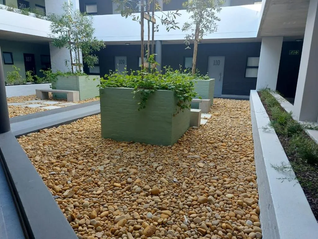 Modern apartment courtyard with gravel, planted containers, and unit entrances
