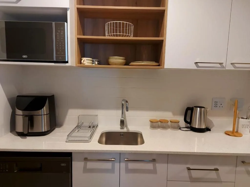Modern kitchen with white cabinetry, stainless steel appliances, and wooden shelving