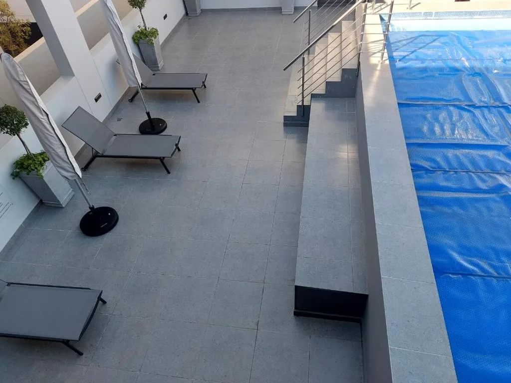 Covered swimming pool with blue protective mesh on modern deck area