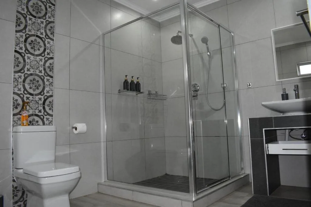 Modern bathroom with large glass shower enclosure and white toilet