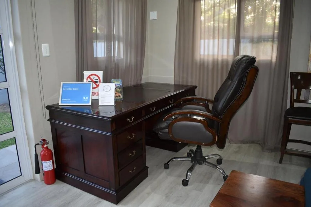 Spacious home office with dark wood desk, leather chair, and natural light