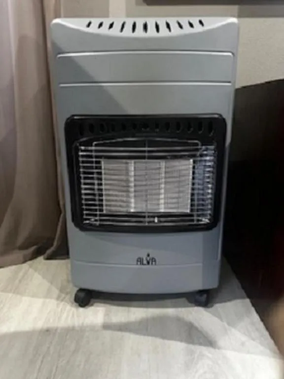 Portable gas heater with glowing burner element indoors