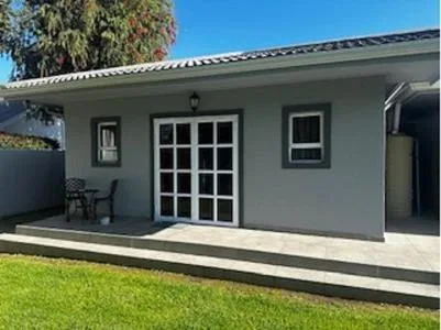 Modern gray cottage with white-trimmed doors and manicured green lawn