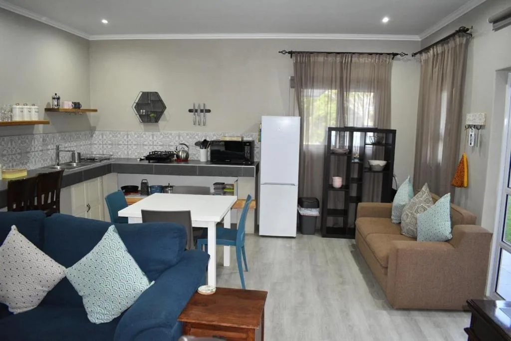 Modern lounge with blue sofa, brown armchair, and open-plan kitchen dining area