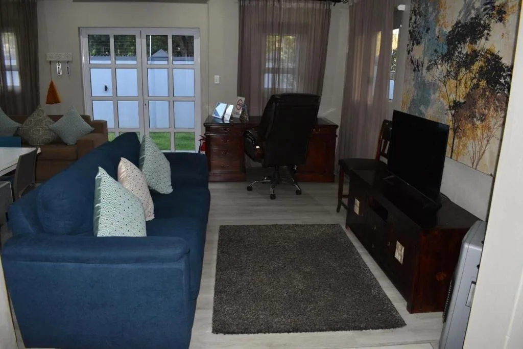 Spacious living room with blue sofa, TV, and garden doors
