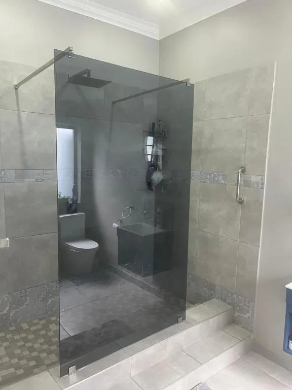 Modern bathroom with large walk-in shower, glass enclosure, and white tile walls