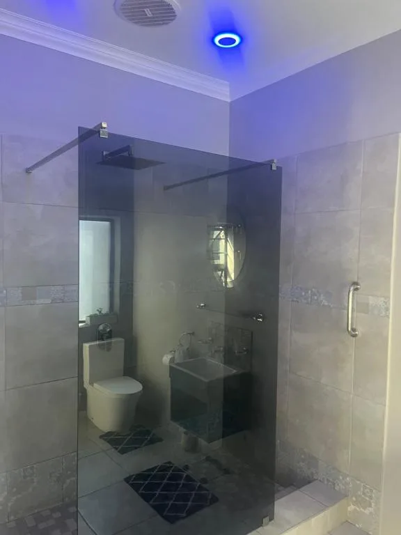 Modern bathroom with glass shower enclosure, toilet, and vanity sink
