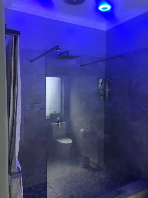 Modern bathroom with glass shower enclosure and ambient blue lighting