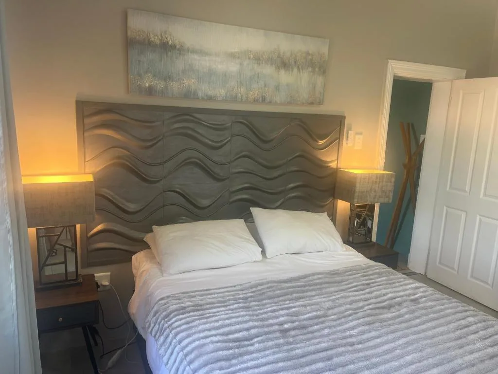 Spacious bedroom with sculptural headboard and warm bedside lighting