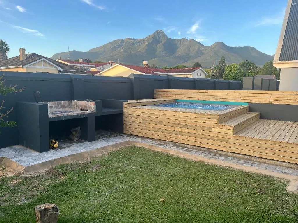Wooden deck with built-in pool, braai area, and mountain views