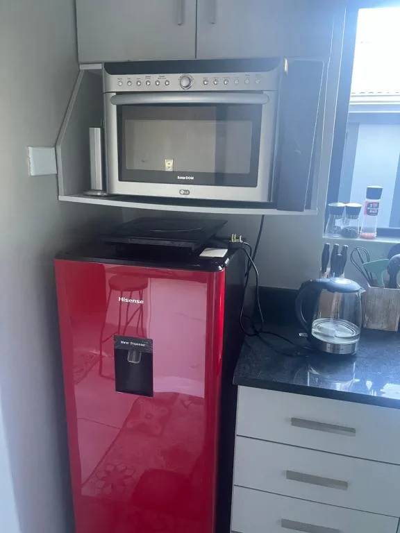 Modern kitchen with built-in microwave and red compact refrigerator