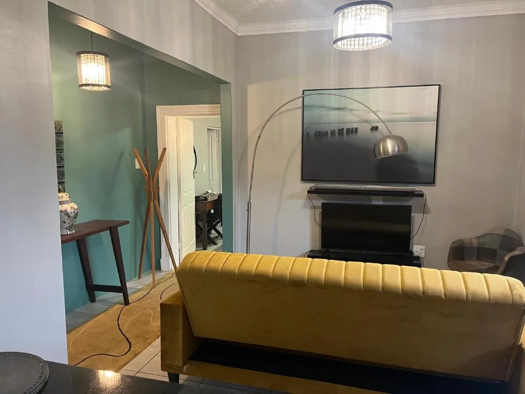 Modern living room with mustard sofa, wall-mounted TV, and contemporary arc lamp