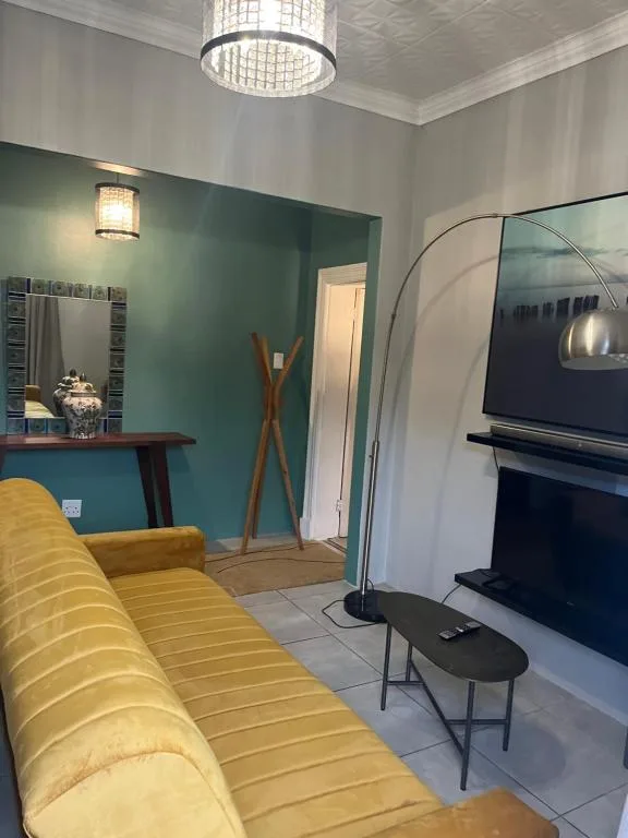 Modern lounge with yellow sofa, fireplace, teal accent wall, and contemporary lighting