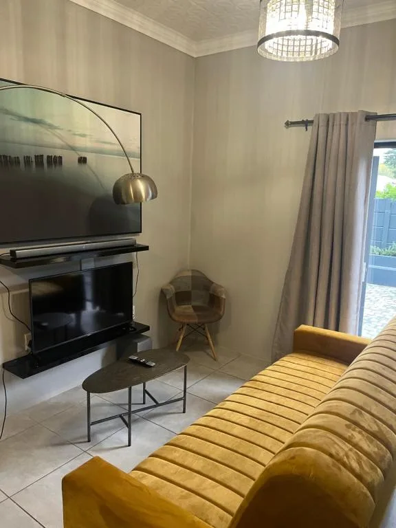 Modern living room with yellow sofa, fireplace, and mounted television