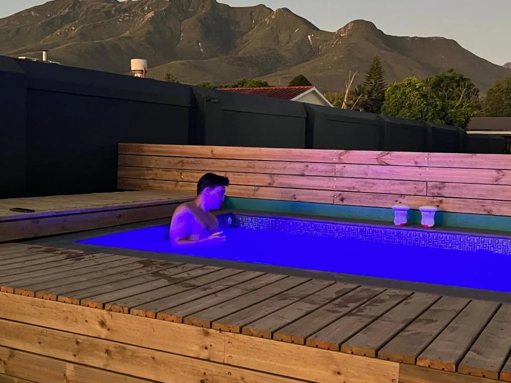 Illuminated swimming pool at dusk with mountains visible in background