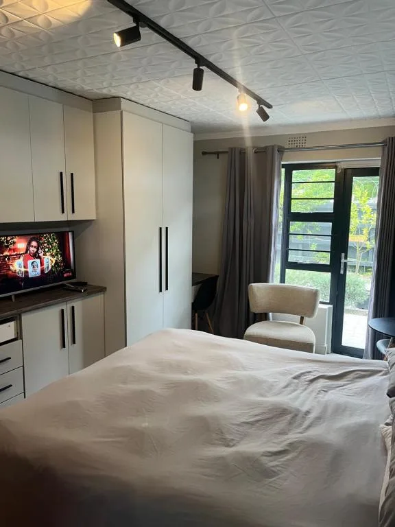 Modern bedroom with bed, built-in wardrobes, and garden view doors