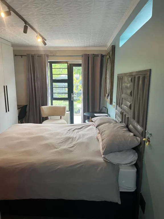 Modern bedroom with queen bed, glass doors opening to garden views