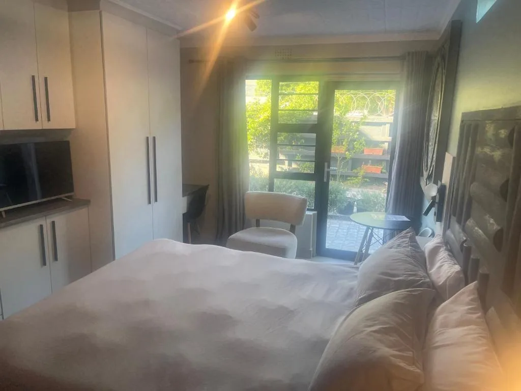 Spacious bedroom with king bed, built-in wardrobes, and garden view doors