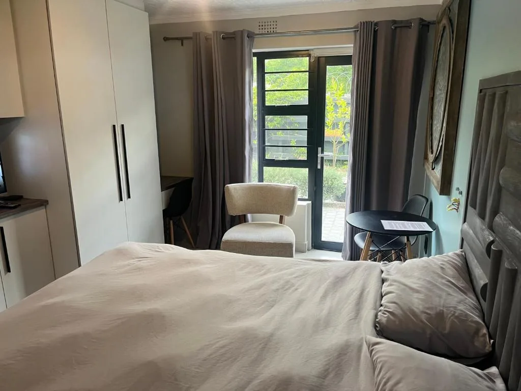 Modern bedroom with queen bed, garden view doors, kitchenette and seating area