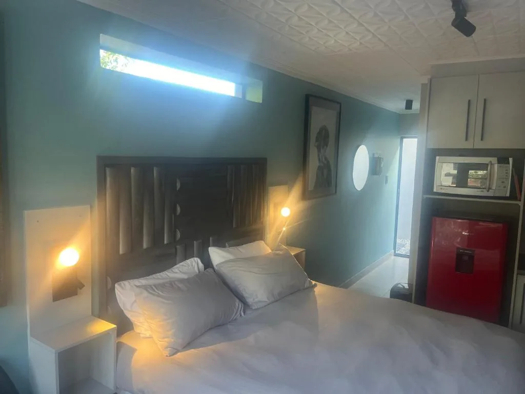Modern bedroom with queen bed, teal walls, and warm bedside lighting