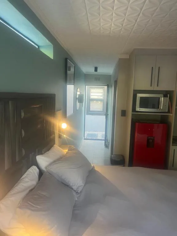 Compact studio bedroom with bed, kitchenette, and modern ceiling lighting