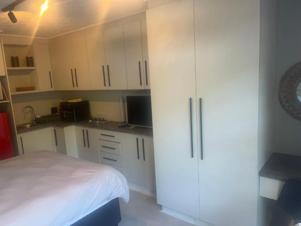 Studio bedroom with modern white cabinetry and kitchenette area