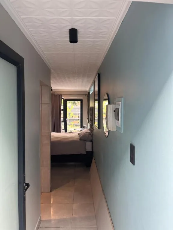 Narrow hallway leading to bed with garden view through window
