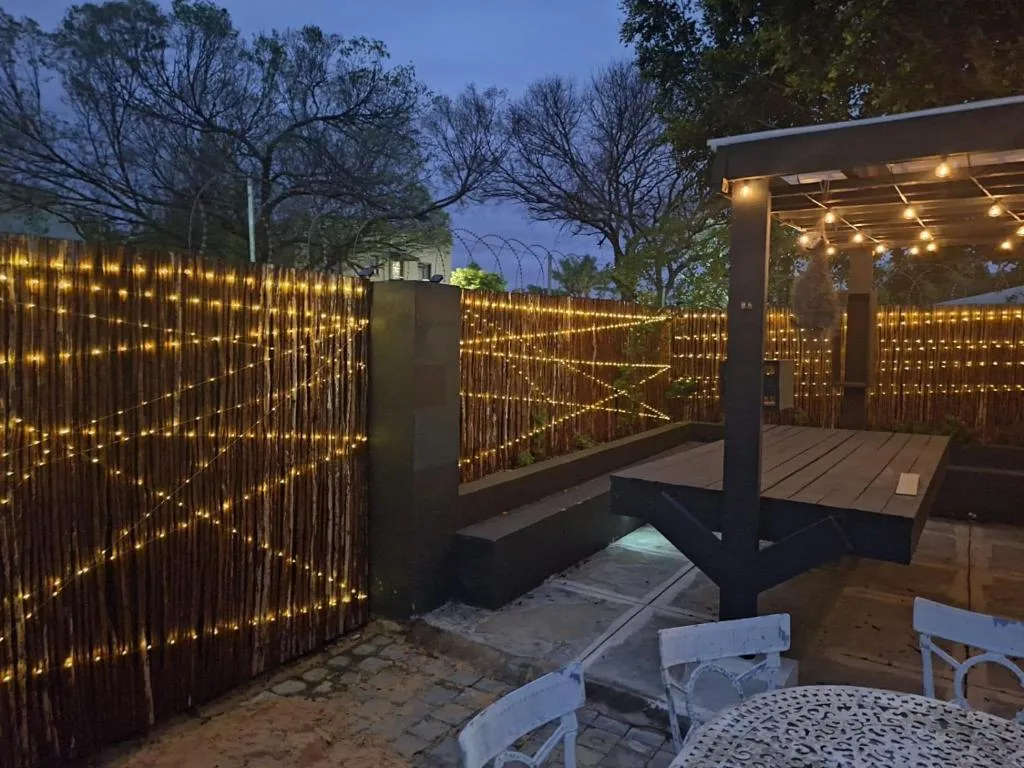 Illuminated outdoor deck with wooden screens, pergola, and seating area at dusk