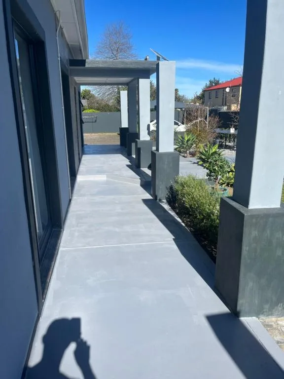 Modern covered patio walkway with concrete flooring and contemporary pergola structure