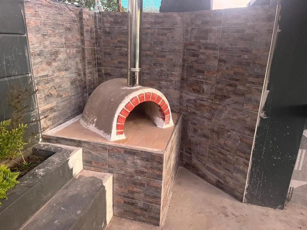 Traditional wood-fired brick pizza oven in enclosed outdoor entertainment area
