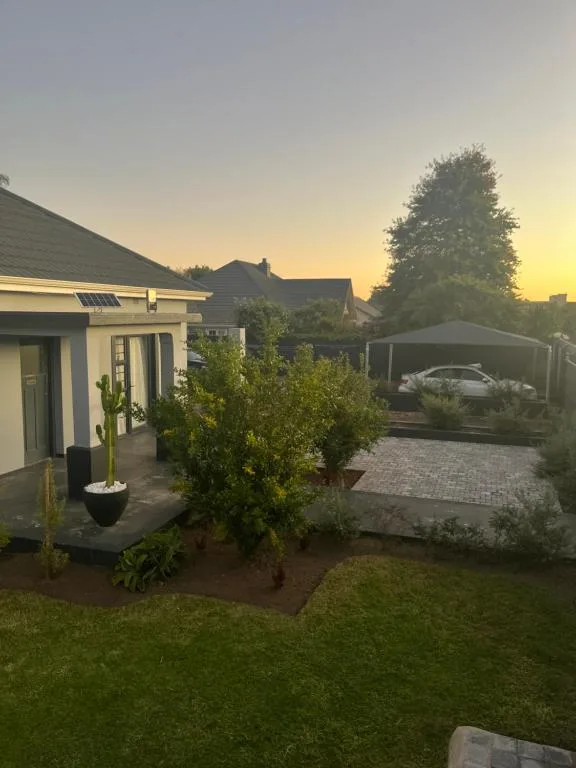 Modern luxury studio with landscaped garden and carport at golden hour sunset