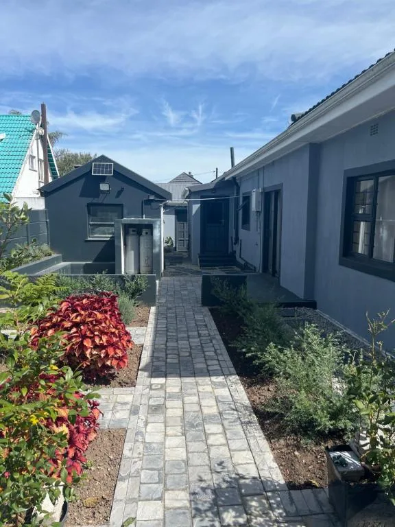 Modern dark blue cottage with paved pathway and flowering garden beds