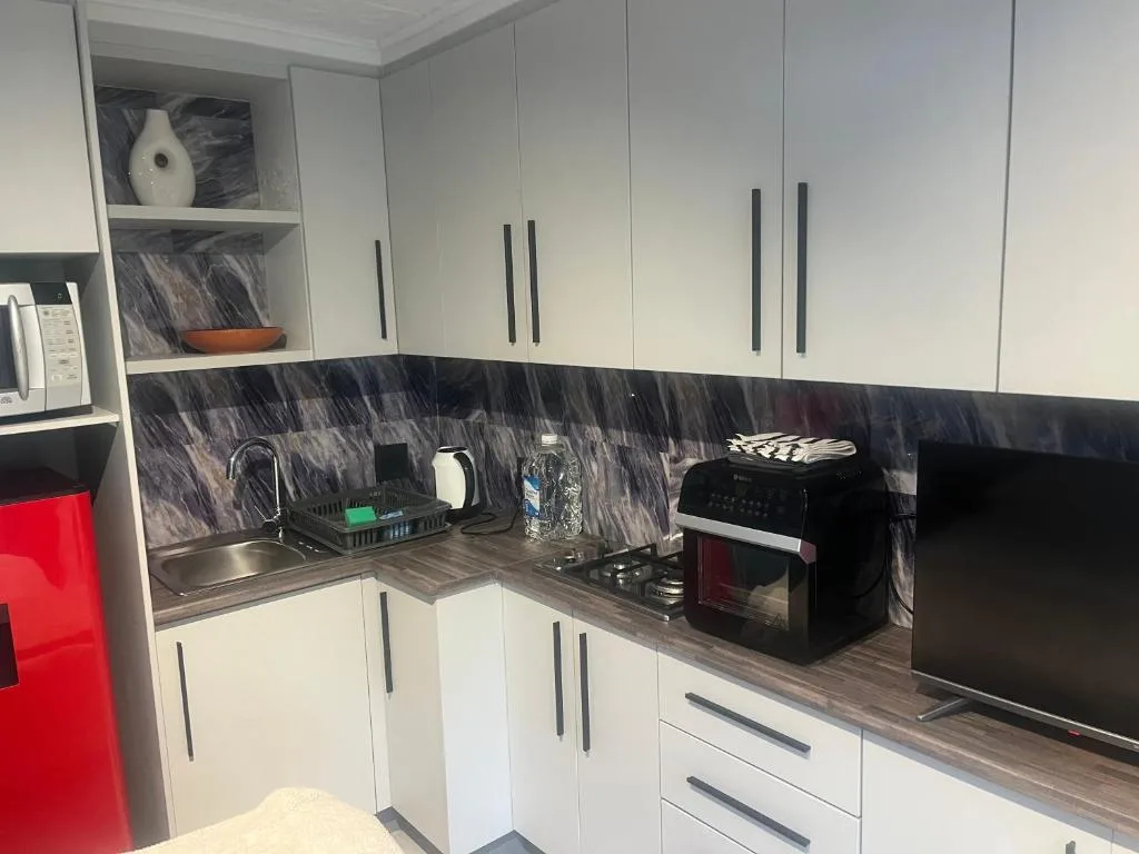 Modern kitchen with white cabinetry, black marble backsplash, and stainless steel appliances