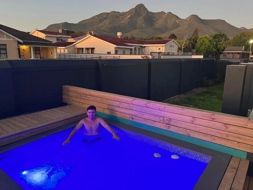 Illuminated swimming pool with wooden deck and mountain backdrop
