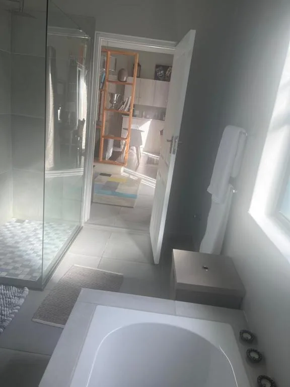 Modern bathroom with bathtub, glass shower enclosure, and wooden storage shelving