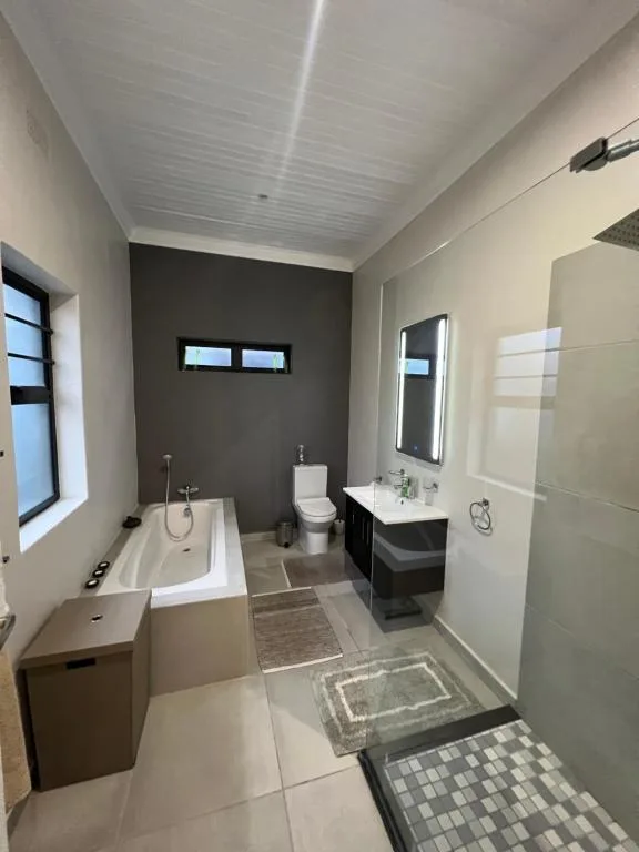 Modern bathroom with bathtub, toilet, vanity sink, and mirror