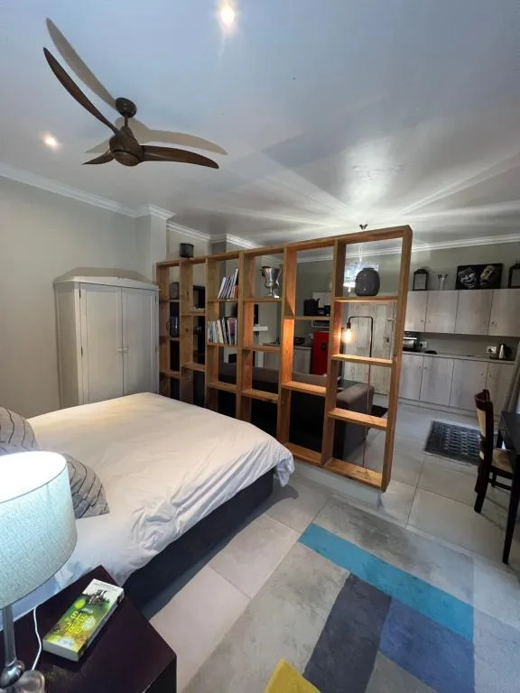 Spacious bedroom with queen bed, ceiling fan, and wooden storage shelving unit