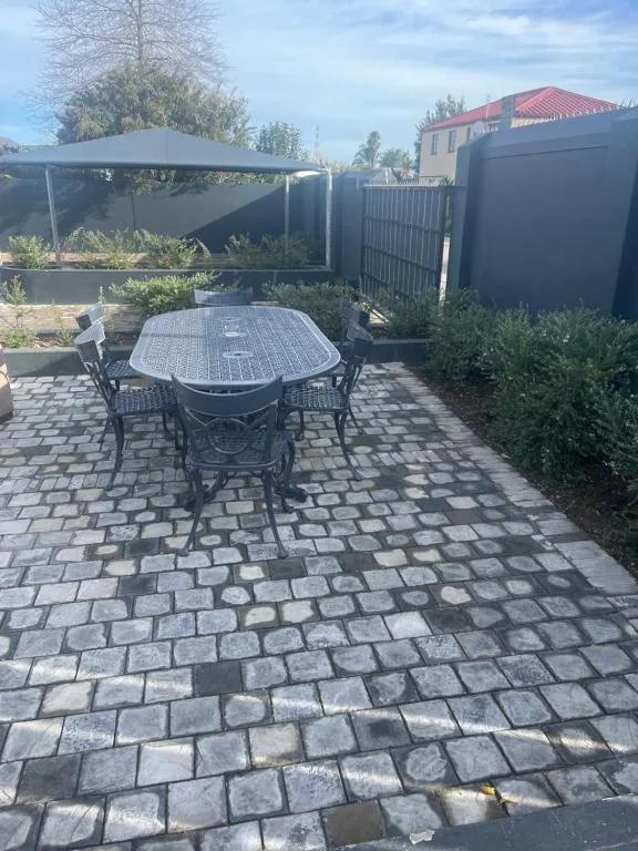Paved patio with dining table, chairs, and shade structure