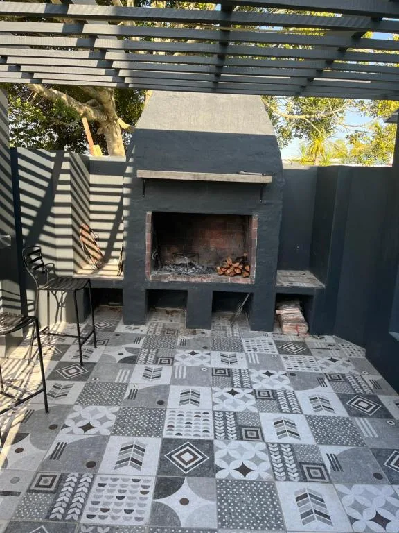Outdoor patio area with fireplace, pergola, and patterned tile flooring