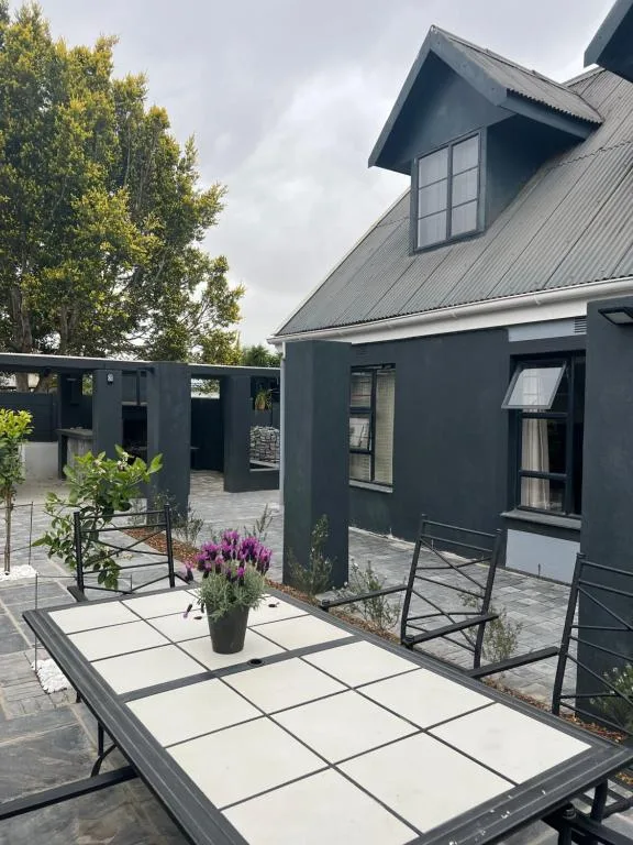 Modern patio with paved seating area and potted flowering plants near home