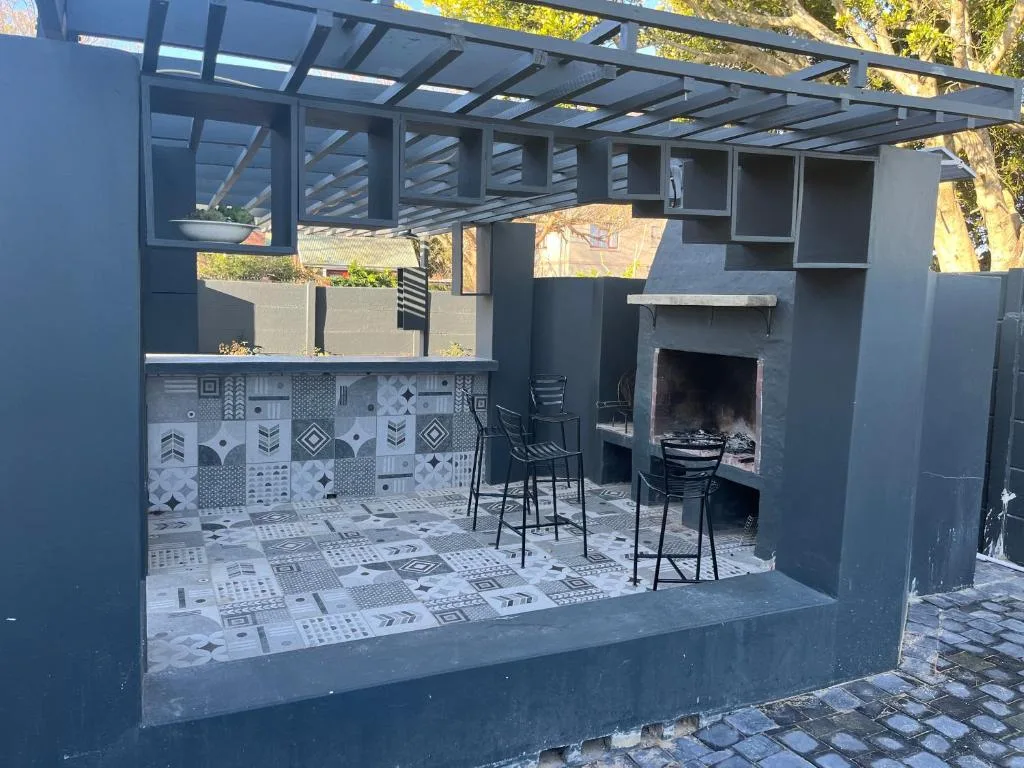 Modern outdoor entertaining area with braai fireplace and patterned tile flooring