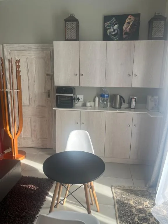 Modern studio kitchenette with white cabinetry and contemporary dining chair