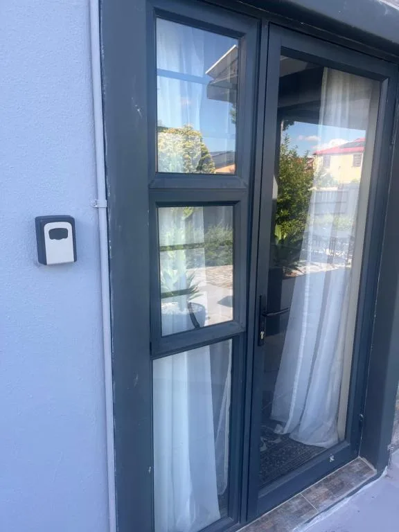 Dark-framed glass entrance door with white curtains and outdoor patio access