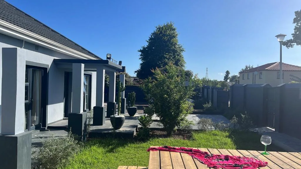 Modern white and black cottage with manicured garden and wooden deck area
