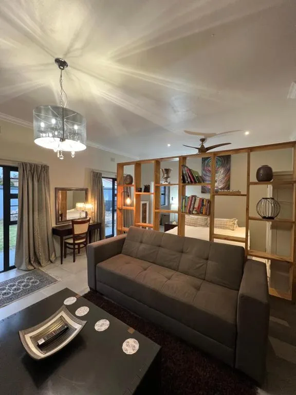 Modern lounge with dark sofa, pendant lighting, and wooden room divider shelving