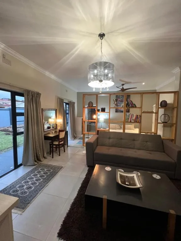 Modern living room with gray sofa, pendant light, shelving unit, and garden view